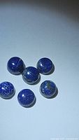 Six natural round cabochon lapis lazuli gemstones, showing their size, color, and smooth polished round shape.