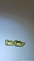 Two emerald cut lemon citrine gemstones with light yellow color on a white background under natural light.