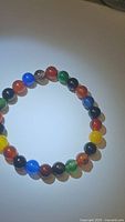 Photo showing the full circular stretchy bracelet composed of polished, multicolored 8mm round agate beads representing different shades of the rainbow.