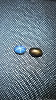 Pair of natural star sapphires photographed on textured dark background, showing distinct star effects on blue and golden black stones