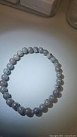 Natural Yooperlite stretchy bracelet laid flat on a surface, showing round grey beads with natural spotting and patterns.