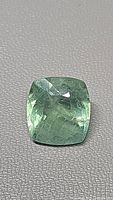 Cushion-cut fluorite gemstone showing seafoam green color and visible inclusions.