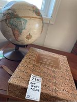Photo of the globe and boxed art books set on wooden table, showing the size and presence of both items.