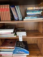 Bookshelves showing mixed hardcover books including dictionaries, nature books, and atlases
