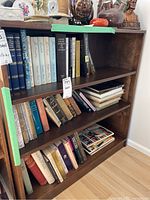 Full view of wood bookshelf filled with books and decorative items on top, showing dark brown wood finish and adjustable shelves.