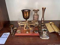 Overview of all brass items including scale, candleholders, vase, goblet, and crumb collector tray arranged on a wooden surface.