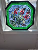 Frontal view of entire octagonal stained glass panel showing floral design and green border