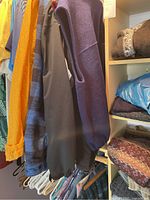 Men's clothing hanging on hangers including short sleeve shirts, jackets in various colors and patterns.