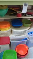 Plastic storage containers with lids on floor, various sizes and colors