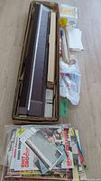 Overview of the Singer knitting machine, attachments including wooden tools and plastic bags, plus a collection of knitting books.