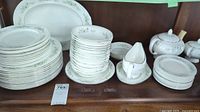 Full set of Wedgwood dinnerware arranged on wooden surface including various sizes of plates, bowls, cups, and saucers showing floral and silver trim pattern.