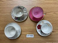 Four bone china tea cup and saucer sets arranged on wood table, viewed from top