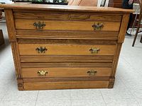 Front view of antique solid wood dresser with three drawers and metal handles.