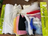Box with assorted fabric pieces showing various colors and textures including lace, felt, cotton, and feather trims