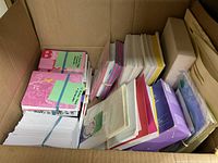 Box with assorted greeting cards in various colors and designs organized in stacks.