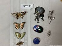 View of all nine brooches displaying butterfly, floral, and abstract designs