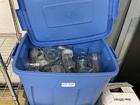 Blue plastic bin filled with clear glass canning jars and metal lids, view from above and front showing quantity and condition.