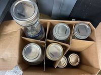 Photo of canning jars with metal lids in cardboard box compartments