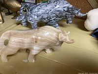 Carved bull figurines, light beige with banding and gray with marbled texture shown from side view.