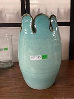 Full view of the ceramic vase showing its rounded body and unique wavy rim with blue glaze and darker edges.