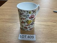 Front view of white bone china mug with colorful detailed floral and butterfly patterns.