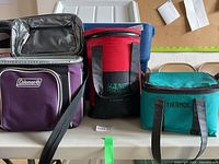 Front view of three soft side coolers on table, showing logos and condition