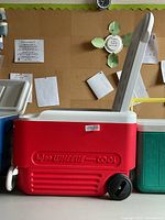 Full side view showing red body, white lid open, wheel and handle attached