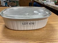 White oval Corning Ware casserole dish with vertical ribs and fitted clear glass lid shown from side.