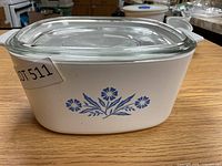 Front view of the Corning Ware square casserole showing blue floral design and glass lid on wooden surface