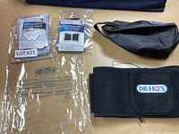 Photo showing two sealed packs of replacement TENS pads, one sealed pack of pain therapy belt pads, the therapy belt, and a clear plastic bag with Dr. Ho's branding.