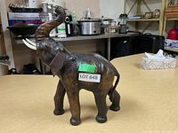 Elephant figurine standing on table with raised trunk, tusks and ears visible, in good condition.