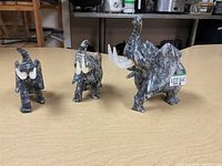 Three elephant figurines on a wooden surface, showcasing varying heights and stone material.
