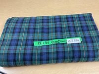 Folded flannel duvet cover with a green tape label showing the size 82 x 88 and description 'Duvet Cover Flannel'. The plaid pattern with blue and green is visible.
