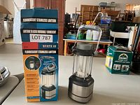 Photo of boxed North 49 fluorescent stainless lantern and the lantern itself on a table.