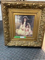Full view of framed artwork on carpeted floor revealing ornate gold frame and traditional portrait.