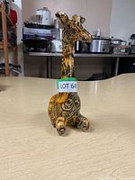 Front angle view of the giraffe figurine showing the detailed animal print pattern and the attached lot number sticker.