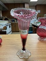 Front view of the cranberry glass vase showing the ruffled top and clear textured base.