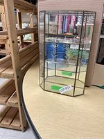Glass display case on table, showing front and sides with etched floral design.