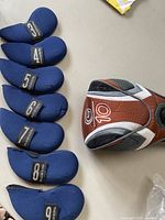 Six blue neoprene golf club headcovers numbered 3,4,5,7,8,9 and one club headcover marked 10