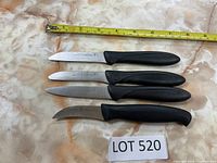 Four Henckels knives with black handles and blades aligned with a measuring tape above showing around 7 inches longest length.