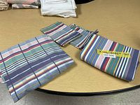 Photo of the folded sheets and pillowcases with visible multicolored stripes laid out on a brown surface.