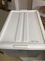 Top view photo of the white lid on the large plastic storage bin with a visible lot number sticker.