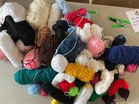 Large assortment of yarn skeins and balls in multiple colors and fibers laid out on tabletop
