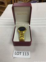 Gold tone Louis Delon wristwatch with blue dial inside a red Louis Delon branded watch box.