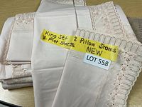 Pile of king size sheets and pillow shams with visible care label indicating "King set 2 Pillow shams 2 Flat sheets NEW"