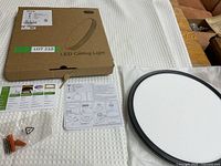Contents of the LED ceiling light package including light fixture, hardware, and instructions.