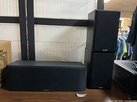 The Paradigm speakers arranged on a table: one horizontal center channel and two standing floor speakers.