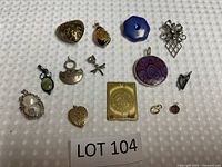 14 assorted pendants laid on paired fabric textured backgrounds, showing full lot variety and condition