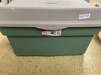 Front view of Rubbermaid Roughneck storage bin with beige lid and green body