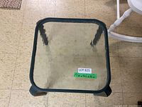 Top view of the small outdoor table showing square textured glass top and metal frame.